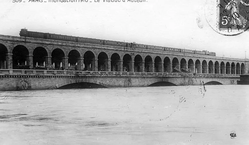 Un train de la Petite Ceinture franchit le pont-viaduc du Point du Jour sur la Seine pendant l'inondation de 1910